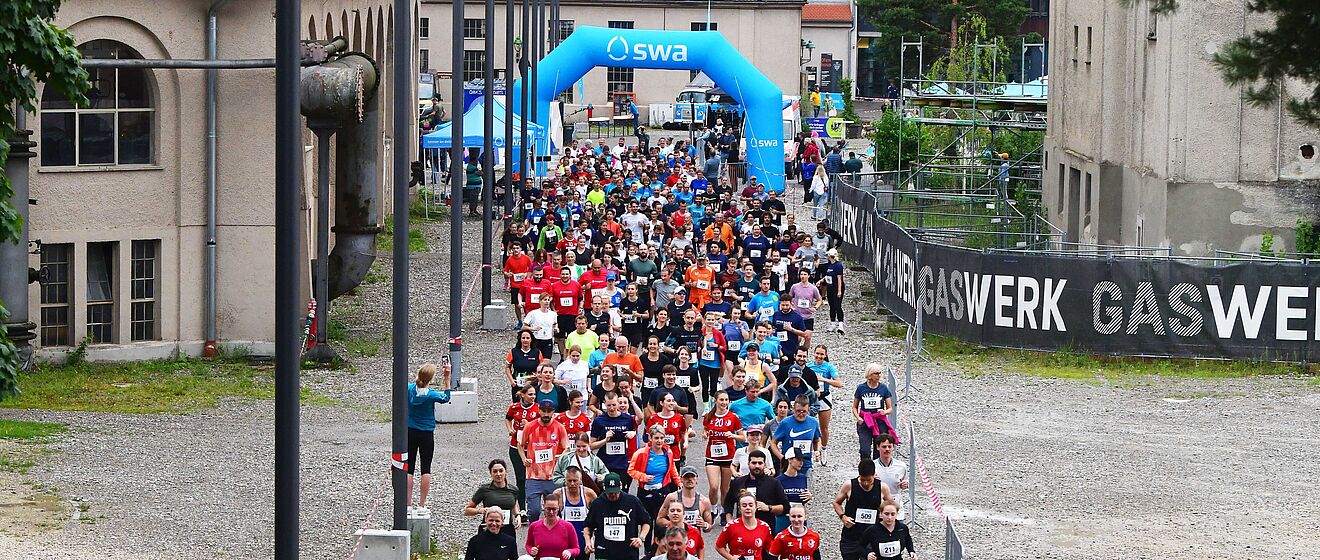 Läufer mit swa Trikot laufen beim swa Spendenlauf. Im Hintergrund ist das Ziel mit swa Branding