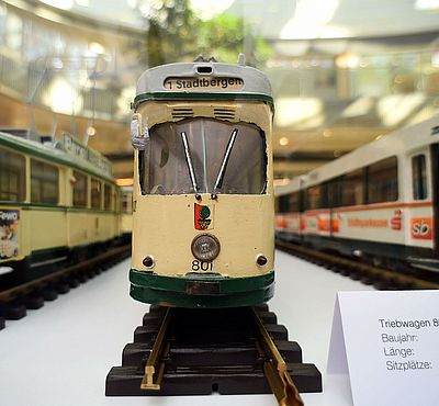 Drei kleine Straßenbahn-Modelle, welche nebeneinander auf Schienen stehen.