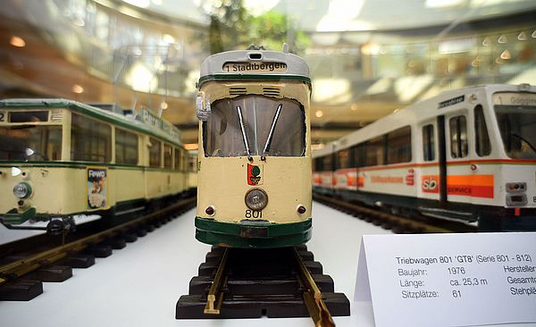 Drei kleine Straßenbahn-Modelle, welche nebeneinander auf Schienen stehen.