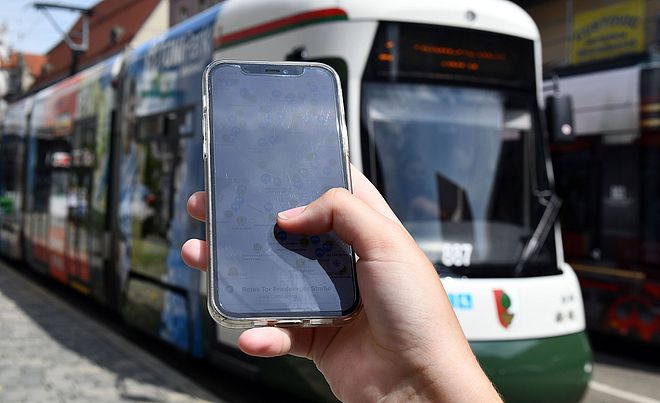 Nahaufnahme eines Handyscreens, auf dem die swa MobilApp gezeigt wird. Im Hintergrund eine swa Tram.