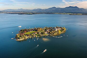 Insel im Chiemsee mit Gebäuden. Die Insel ist umgeben von Booten. Ein Klick sorgt für eine Großansicht des Bildes