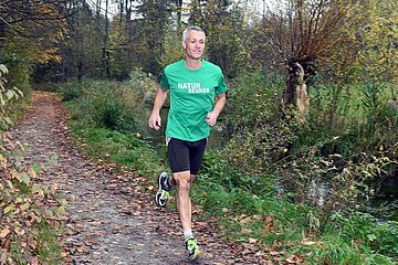 Mann joggt neben Brunnenbach. - Ein Klick auf das Bild führt zur vergrößerten Fotoansicht.