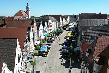 Marktplatz in Günzburg mit vielen parkenden Autos und Sonnenschirmen vor den Gebäuden. Ein Klick sorgt für eine Großansicht des Bildes
