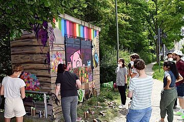 Gruppe betrachtet angesprayte Wand des Technikgebäudes. - Beim anklicken wird das Bild vergrößert.