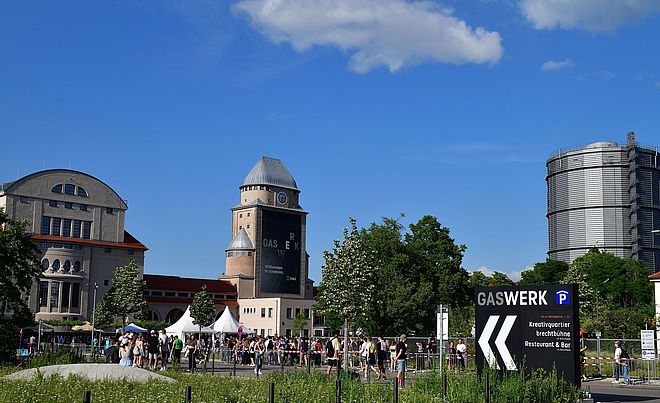 Blick auf das Gaswerksgelände, auf dem junge Menschen zu einer Veranstaltung strömen.