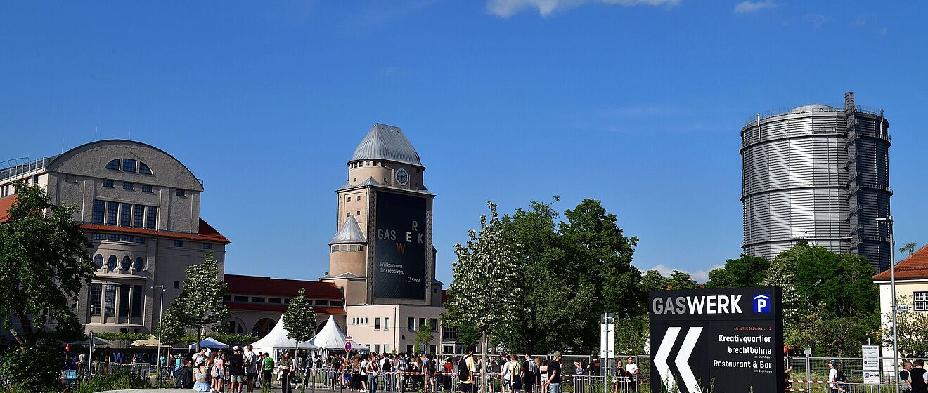 Blick auf das Gaswerksgelände, auf dem junge Menschen zu einer Veranstaltung strömen.