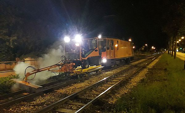 Ein Schienenfahrzeug in orange fährt bei Nacht.
