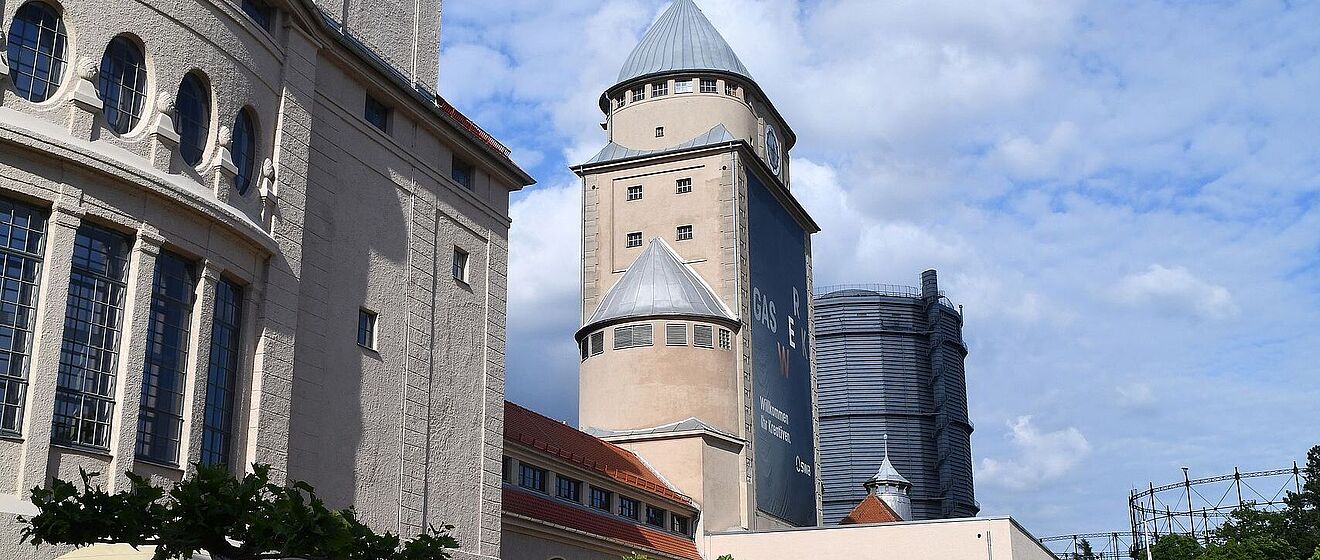 Gaswerksareal mit Sitzmöglichkeiten, Tischen und Sonnenschirmen. Weiterverlinkung auf Gaswerksareal Newsartikel