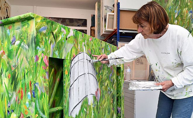 Frau mit Pinsel bemalt ein Klavier mit grüner Farbe. Weiterverlinkung auf Kunst im Gaswerk Newsartikel