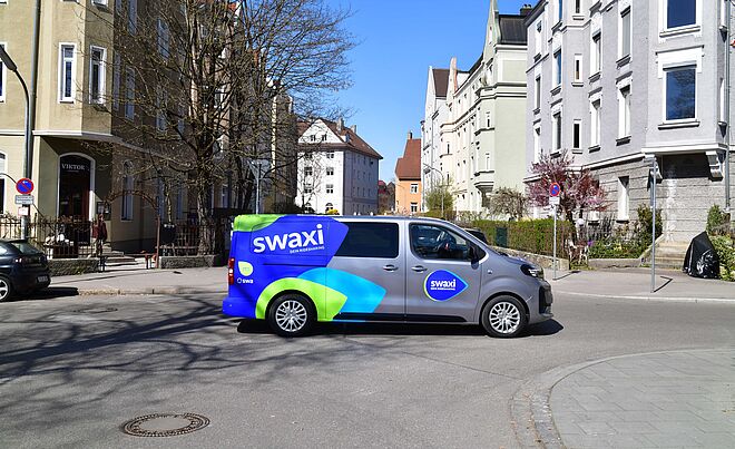 swaxi Auto steht auf der Straße im Bismarckviertel in Augsburg. Im Hintergrund sind Wohngebäude