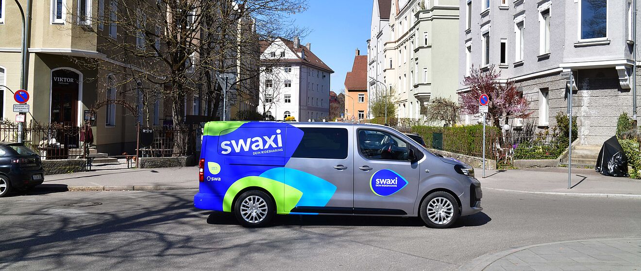 swaxi Auto steht auf der Straße im Bismarckviertel in Augsburg. Im Hintergrund sind Wohngebäude