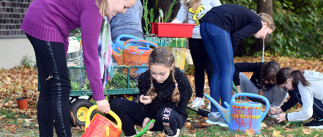 Verschiedene Kinder und Erwachsene beteiligen sich an einer gemeinschaftlichen Pflanzaktion im Freien.