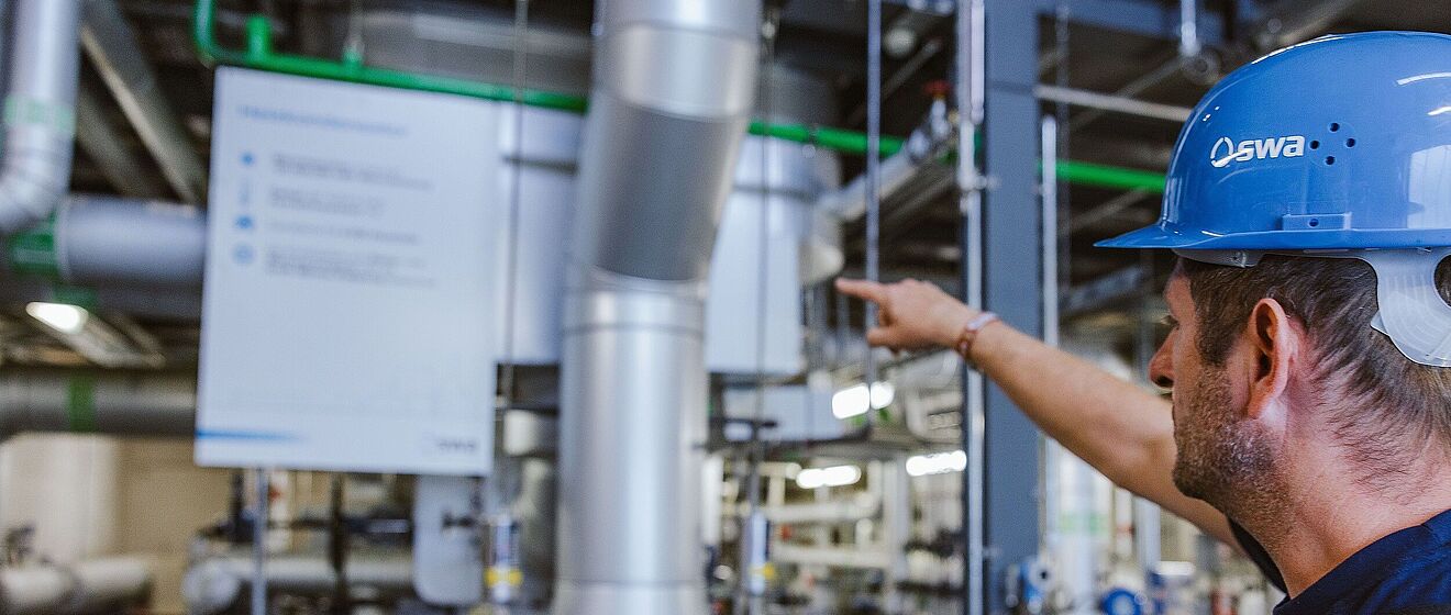 Mann mit Helm zeig auf Anlagen der Netze.