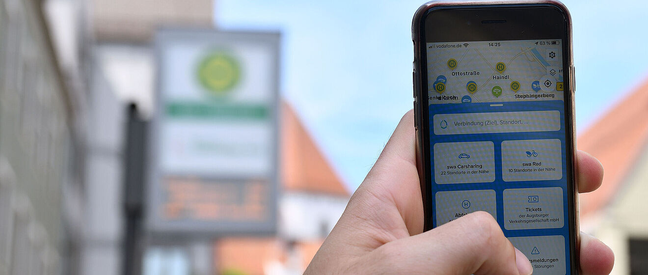 Ein Hand hält ein Handy in die Luft. Auf dem Display sieht man, dass die swa MobilApp genutzt wird.