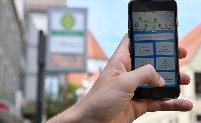 Ein Hand hält ein Handy in die Luft. Auf dem Display sieht man, dass die swa MobilApp genutzt wird.