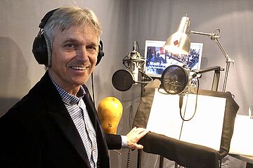 Person mit Kopfhörern vor einem Mikrofon