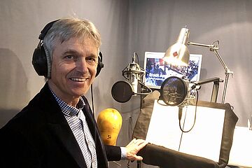 Person mit Kopfhörern vor einem Mikrofon