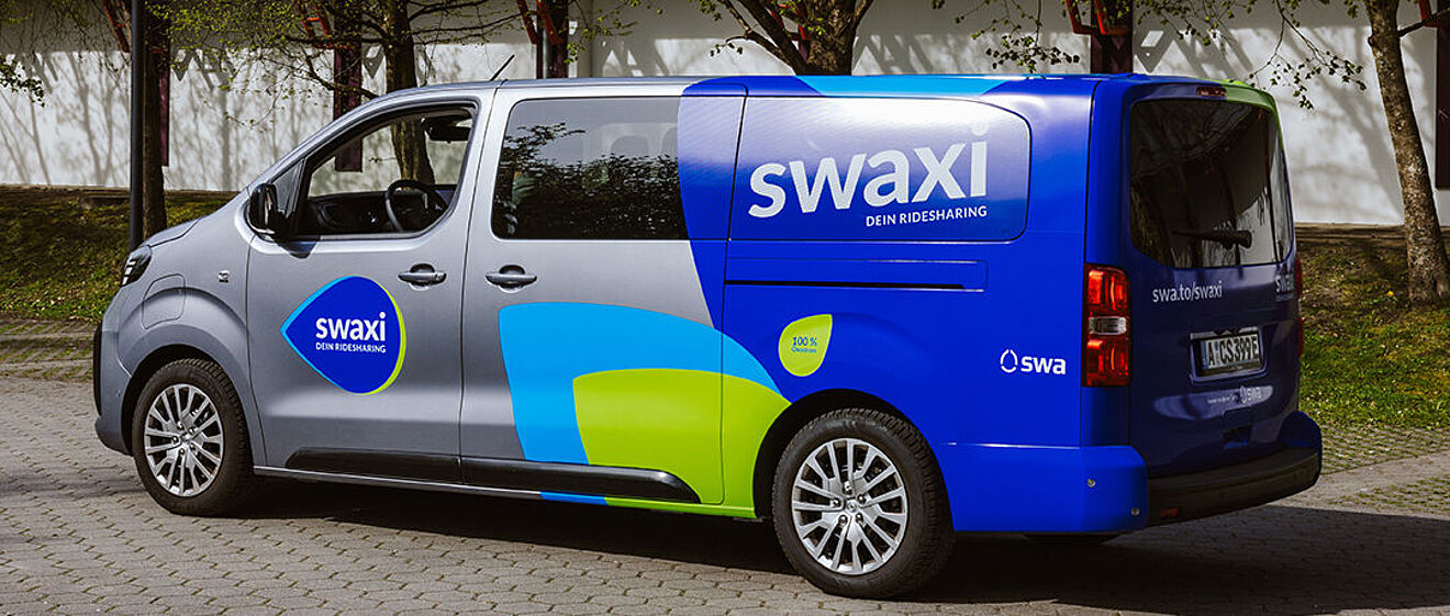 swaxi Transporter mit swaxi Branding an den Seite steht auf einem Parkplatz.