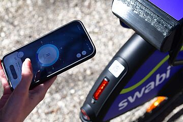 Person steht mit einem Smartphone vor einem swabi. Auf dem Handybildschirm ist die Absperrfunktion in der swabi-App zu sehen.