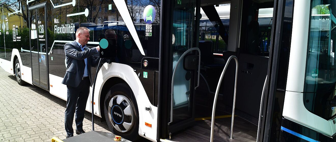 Mann im Anzug verbindet einen neuen swa eBus mit einer Ladebox.