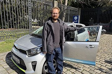 Mann vor einem swa Carsharing Auto mit geöffneter Tür