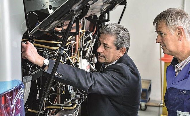 Ernst Schäfer und ein anderer Mann begutachten das Innenleben eines Busses unter der Motorhaube.