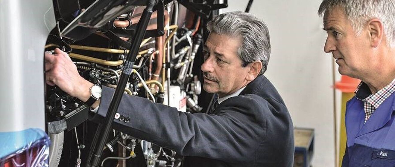 Ernst Schäfer und ein anderer Mann begutachten das Innenleben eines Busses unter der Motorhaube.