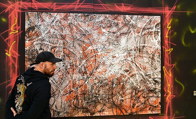 Person steht vor einem Kunstwerk. Weiterverlinkung auf URBAN LOVESTORY Newsartikel