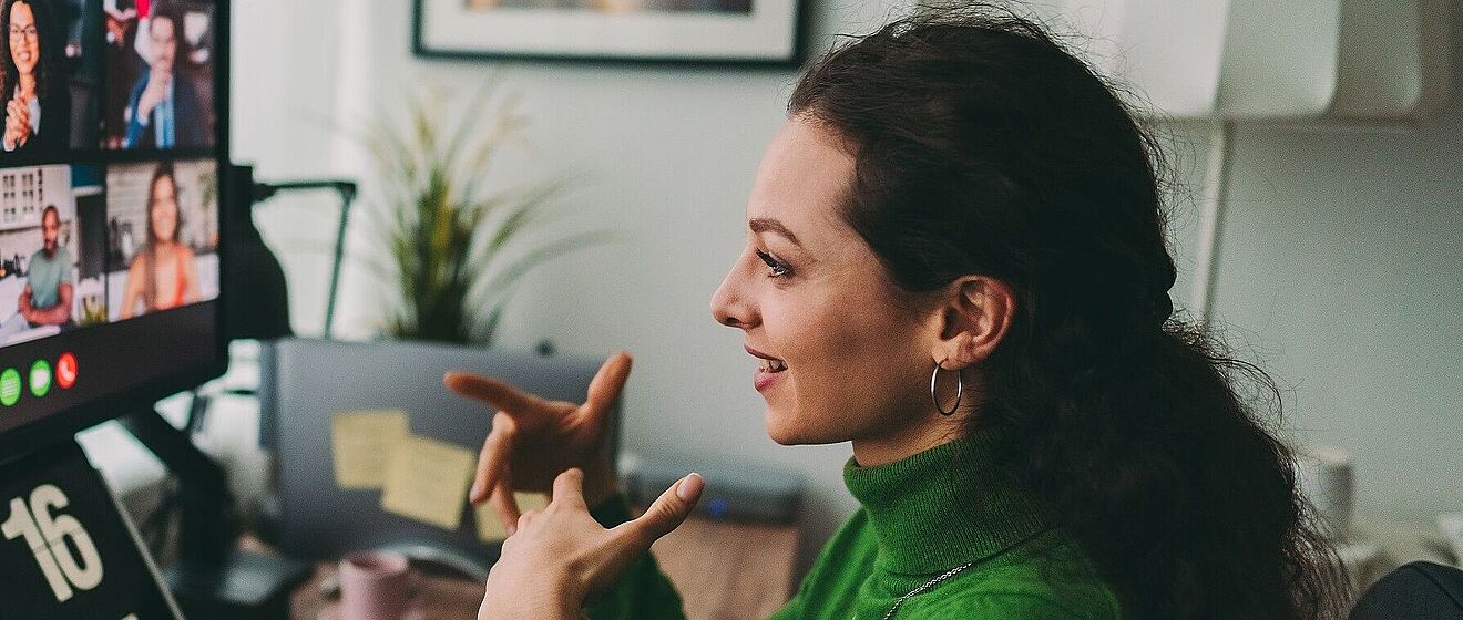 Frau an einem Schreibtisch ist in einem Videomeeting. 