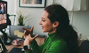 Frau an einem Schreibtisch ist in einem Videomeeting. Link zu einem Pop-Up mit Informationen zu Telefon und Videocall