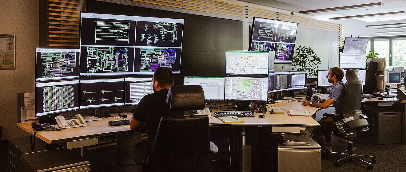 Büro der Netzeleitstelle mit Mitarbeitern an ihren Schreibtischen und vielen Monitoren.