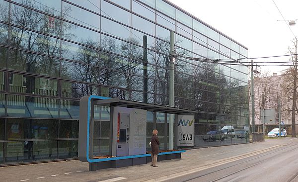 Neue Bushaltestelle vor einem großen Gebäude.