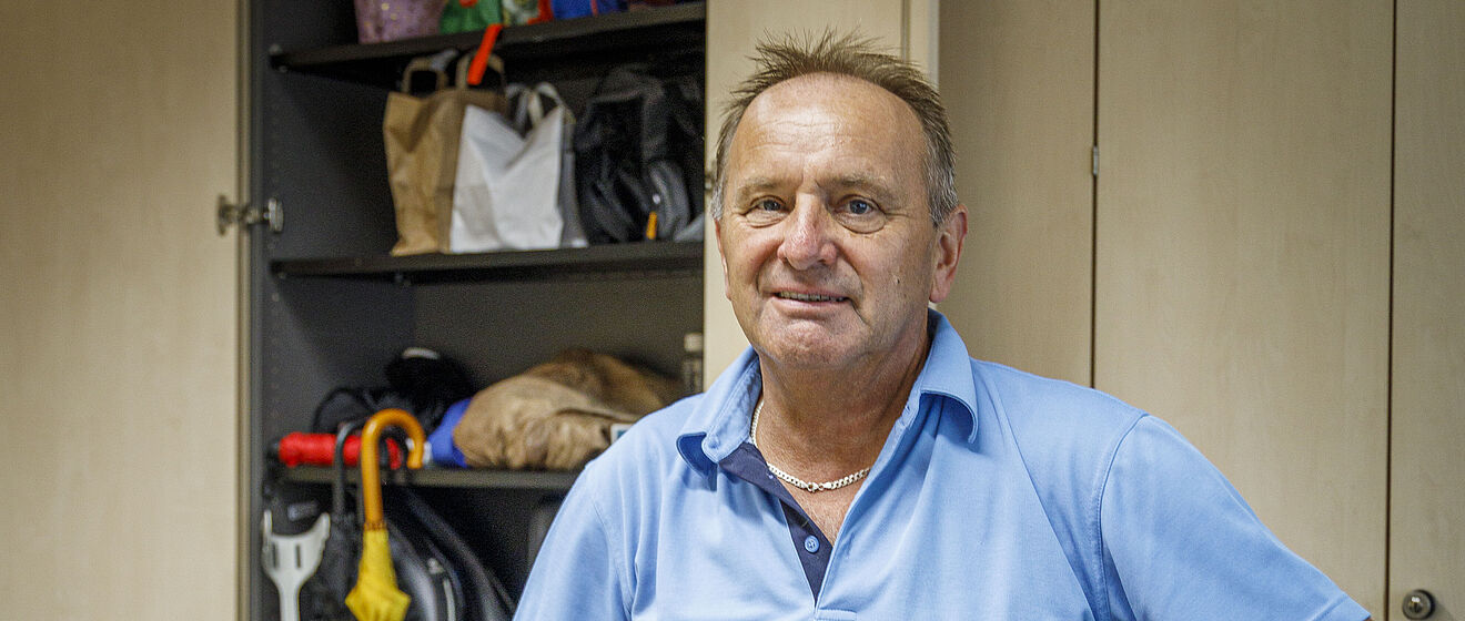 Ein Mann mit blauem T-Shirt steht im Fundbüro der swa, auf dem Tisch liegen Handys und Sonnenbrillen.