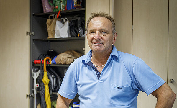 Ein Mann mit blauem T-Shirt steht im Fundbüro der swa, auf dem Tisch liegen Handys und Sonnenbrillen.