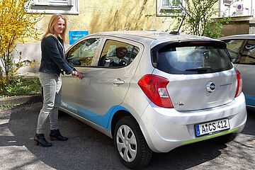 Eine Frau steht neben einem swa Carsharing Auto, mit ihrer Hand am Türgriff. - Ein Klick auf das Bild führt zur vergrößerten Fotoansicht.
