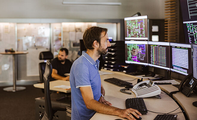 Ein Mann sitzt vor vielen Bildschirmen.