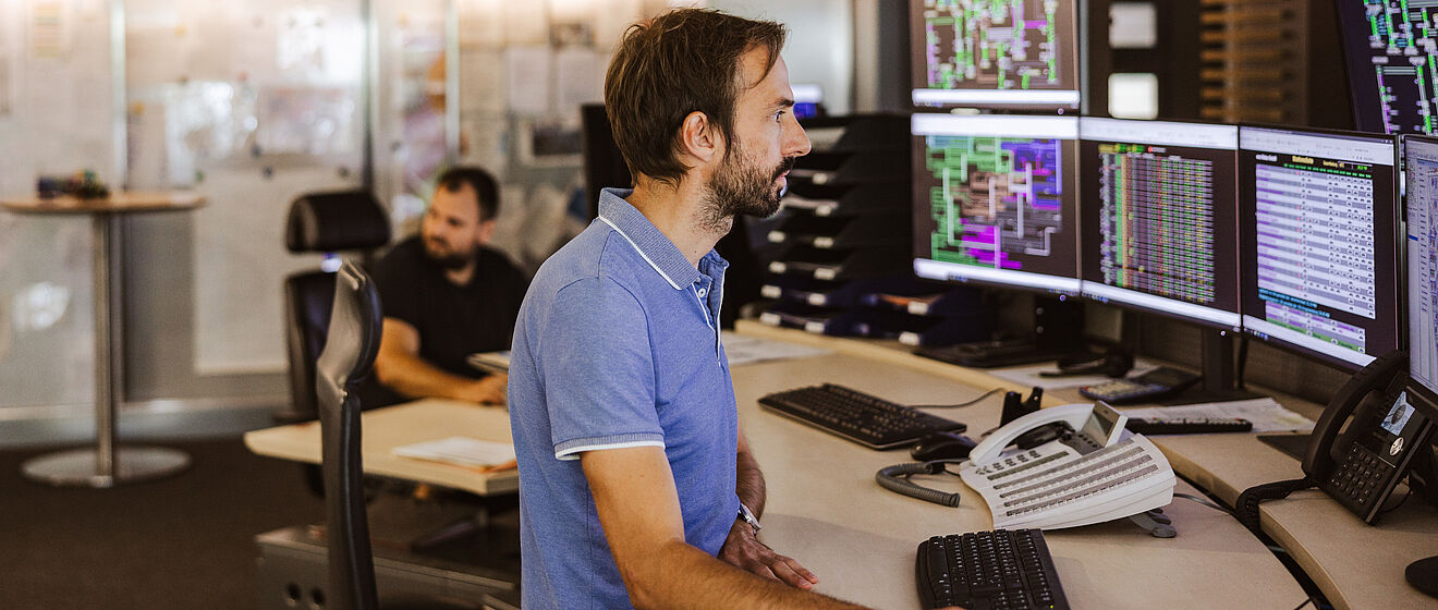 Ein Mann sitzt vor vielen Bildschirmen.