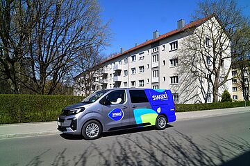 swaxi Auto steht auf einer Straße. Im Hintergrund sind Wohnblöcke