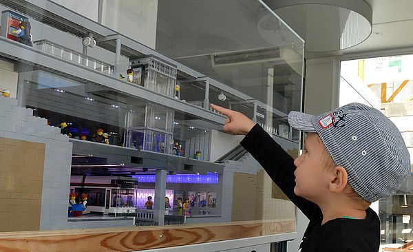 Kind steht am Mini-Hauptbahnhof und schaut ihn sich an.