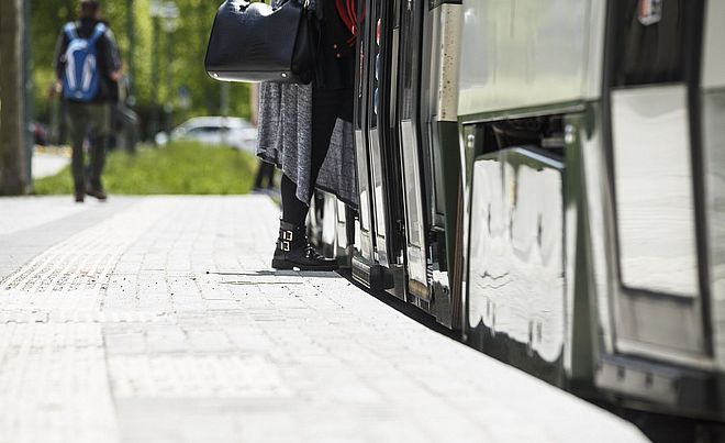Eine Person steigt in eine Straßenbahn der swa ein. auf dem Boden sind Streifen für Barrierefreiheit zu erkennen.