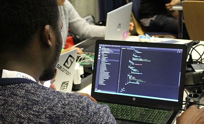 Ein Mann sitzt vor einem Laptop und führt Programmierungen durch.