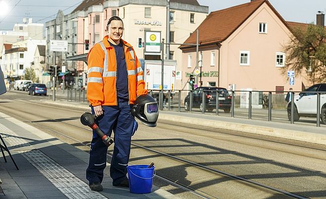 Bauarbeiter steht mit Werkzeug auf einer Haltestelle
