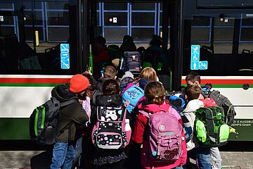 Kinder mit Schulranzen steigen beim Bussicherheitstraining in die hintere Tür eines Busses