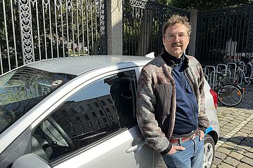 Ein Mann steht vor einem swa Carsharing-Auto