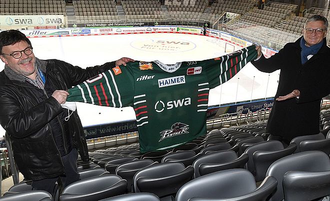 Zwei Männer präsentieren neues AEV-Trikot im AEV Stadion