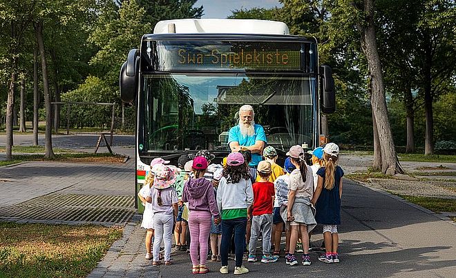 swa Mitarbeiter Andy Adam vor einem Linienbus der swa gemeinsam mit Kita-Kindern