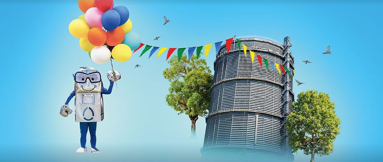 Oswald, das Maskottchen der Stadtwerke Augsburg (swa), posiert vor dem Gaskessel Augsburg mit Luftballons und Partyfahnen.