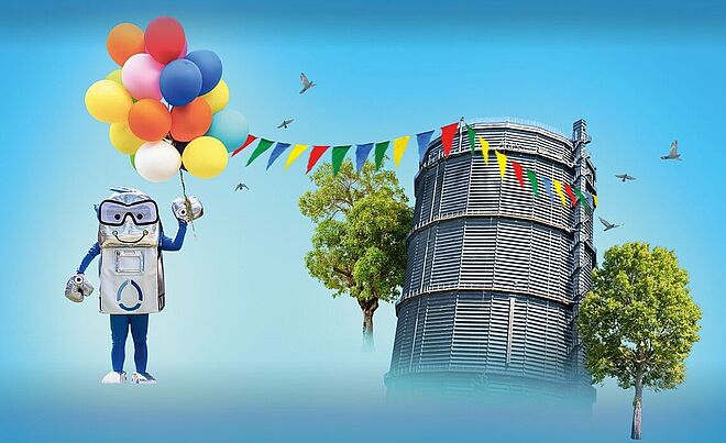 Oswald, das Maskottchen der Stadtwerke Augsburg (swa), posiert vor dem Gaskessel Augsburg mit Luftballons und Partyfahnen.