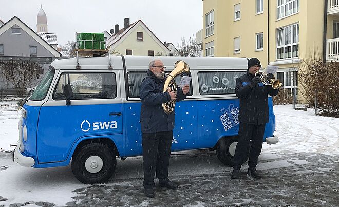 Blasmusiker spielen Musik vor SWA-Wasserbulli