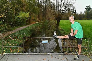 Mann dehnt sich auf einer Brücke über dem Brunnenbach - Ein Klick auf das Bild führt zur vergrößerten Fotoansicht.